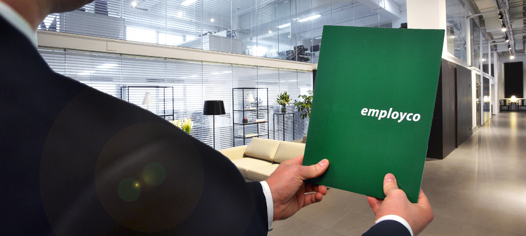 Shoulder shot of man in a suit holding out Employco folder.